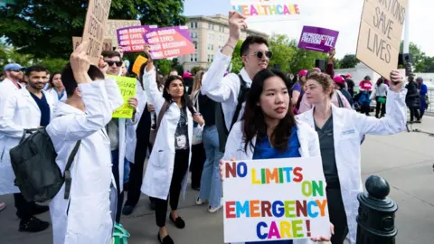 Getty Images People in white jackets hold signs
