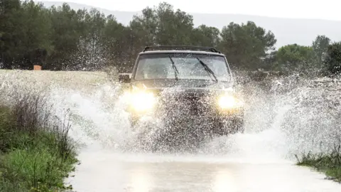 Car driving through water on a road