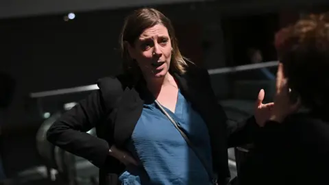 Getty Images Jess Phillips standing up, wearing blue top underneath black blazer. She has one hand on her hip and is facing someone and talking to them.