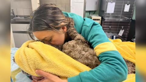 Woman hugging her dog in a blanket