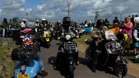 A gathering of dozens of scooters and riders