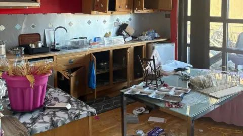 Contributed A kitchen area that with a former tenants items left behind all over the work surfaces and a table. Cupboard doors are open and there are some items on the floor. 