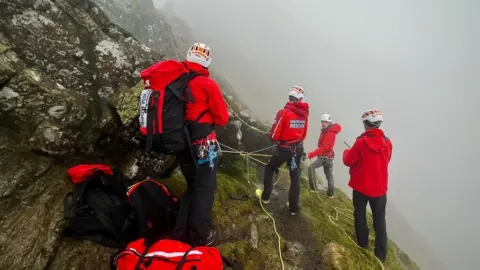 Keswick Mountain Rescue team Rescuers using a rope system to reach the injured woman