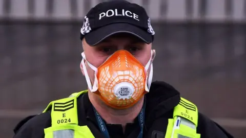 Getty Images A police officer wears a PPE face mask outside the Scottish Parliament as members of the public attend an anti lockdown protest held by The Scotland Against Lockdown group in Edinburgh, Scotland on January 11, 2021.