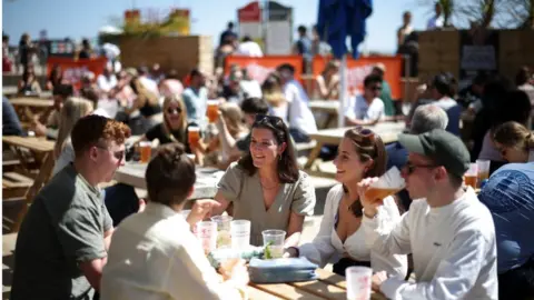 Reuters People sit at an outdoor bar as they enjoy the hot weather on Brighton pier, in Brighton