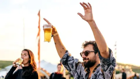 Anna Rachel Photography/Love Trails Man holding a pint of beer above his head