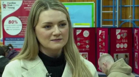 Nicola Rees/BBC A woman with long blonde hair and a cream coat with black jumper