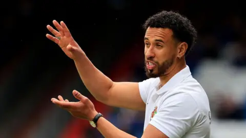 Sam Cox gestures with both hands from the touchline to show his players how he wants them to operate