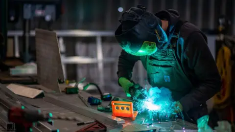 Getty Images Seorang pekerja mengelas bagian -bagian untuk dermaga di toko fabrikasi aluminium di West Coast Floatation dekat Duncan, British Columbia, Kanada, pada hari Selasa, 21 Februari 2023.