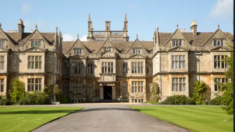 Getty Images A stately home with large windows and a neat lawn and driveway in front of it.
