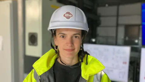 A woman in a white hard hat and high-viz jacket stands in the "powerhouse" at the RheEnergise high density pumped hydro energy storage scheme in Devon