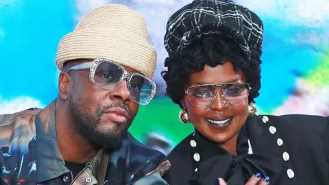 Wyclef Jean and Lauryn Hill leaning together and posing for the camera