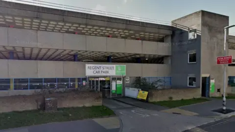 A picture of regent street car park. It is a multi story building with signs and grassland surrounding the area.