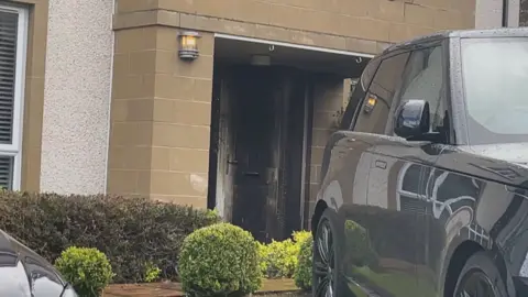 A charred front door at Pitcairn Grove