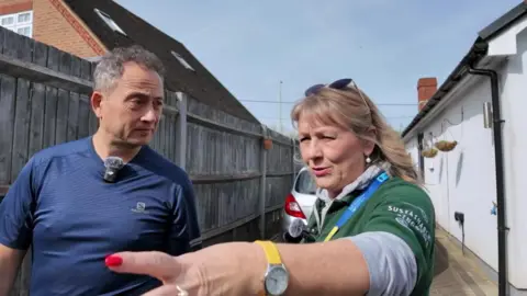 An eco expert points to areas of a resident's garden during a visit.