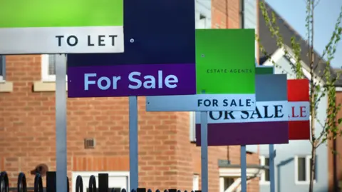 A row of for sale or to let signs outside a new housing development 