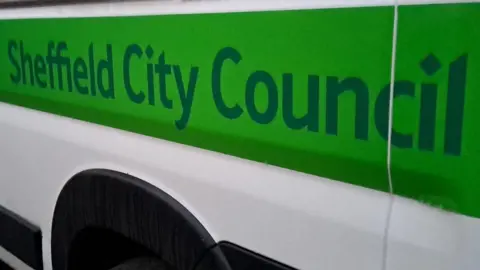 The side of a white minibus has a green sign which says Sheffield City Council