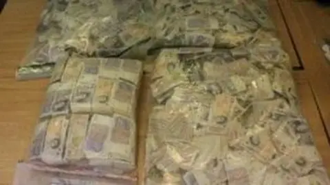 Large piles of UK banknotes in large transparent plastic bags.