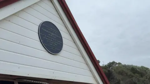 A blue plaque on the front of a beach hut.