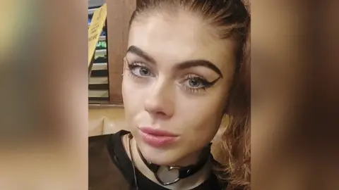 Devon and Cornwall Police Holly Collinson wears flicked eye liner around her blue eyes as she looks directly at the camera 