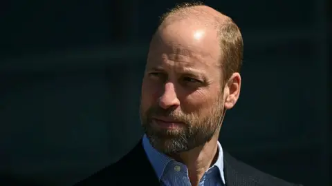 Getty Images Prince William wearing a dark blazer and striped shirt.