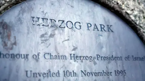 Reuters A metal plaque, the text is barely visible but the words Herzog Park are spelled out, also mention of honour of Chaim Herzog, President of Israel, unveiled 10th November 1995