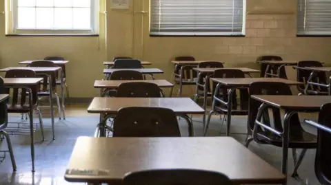 A generic short of a classroom, with rows of individual desks and chairs. 