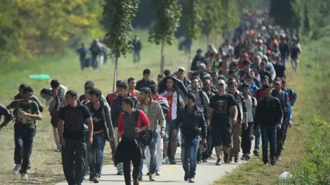 Getty Images Migrants walk from Hegyeshalom on the Hungarian border walk into Austria on 23 September 2015