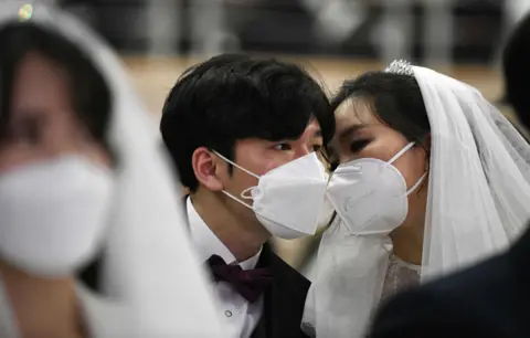 AFP A masked couple share a moment during a mass wedding ceremony organised by the Unification Church in Gapyeong