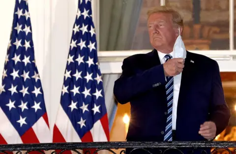 Win McNamee / Getty Images Donald Trump removes his mask upon return to the White House from Walter Reed National Military Medical Center on 5 October 2020