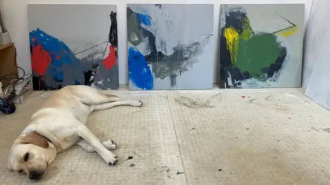 Angela Charles Flynn the guide dog in front of paintings