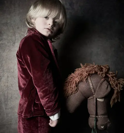 Debbie Todd Austin, from Hexham, wearing a red velvet suit and holding a brown hobby horse