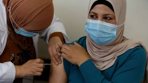 Getty Images A Palestinian healthcare worker administers the Covid-19 vaccine to a patient