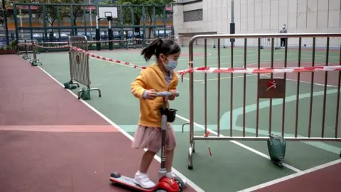 Getty Images A young girl uses her scooter around a roped-off basketball court, closed due to Covid-19