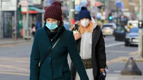 Getty Images Woman in masks walk along a street in London on 21 January 2021