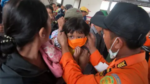 Reuters/Antara An officer with the disaster management agency BPBD places a mask on child at a shelter