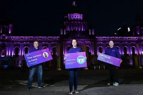 Michael Cooper Dr David Marshall (left), Shauna Dunlop and Conor McKiernan posing in front of Belfast City Hall to promote the census