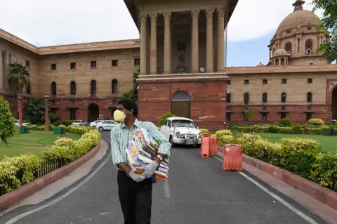 Getty Images A government employee holding files as he comes out from Ministry of Finance at North Block as ministries and government offices partially resume working from office, at Raisina Hills on April 20, 2020 in New Delhi,