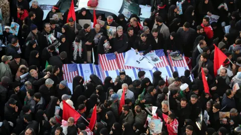 EPA Iranians carry mock coffins with US and Israeli flags in Tehran on 6 January 2020