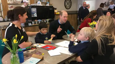 PA Media Prince William enjoys an ice cream while talking to parents