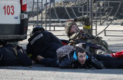 Reuters People take cover as an air-raid siren sounds, near an apartment building damaged by recent shelling in Kyiv, Ukraine February 26, 2022.