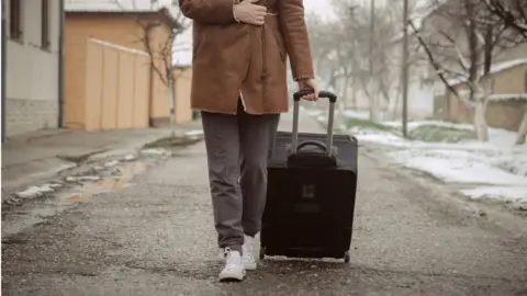 Getty Images Woman dragging suitcase