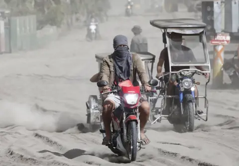 EPA People travel along a road covered in ash deposits, a day after the eruption of Taal Volcano, in Agoncillo town in Batangas province, Philippines, 13 January 2020