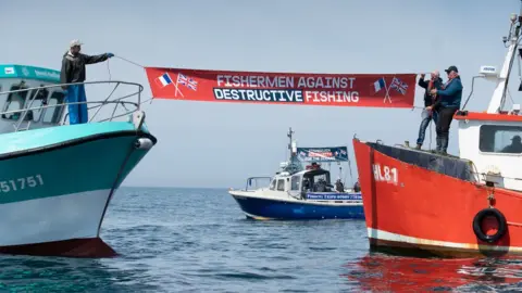 Suzanne Plunkett/Greenpeace A banner being held between two boats in the Channel