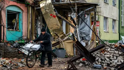 AFP via Getty Images A local resident pushes his bicycle down a street in Bakhmut in January