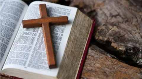 Getty Images An open Bible with a wooden cross on it