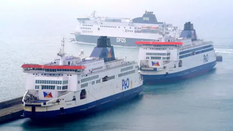 PA Media A DFDS ferry passes the P&O Ferries the Pride of Kent (left) and the Pride of Canterbury (right) moored at the Port of Dover