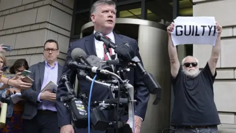EPA Bystander holds "guilty" sign as Kevin Downing, defence lawyer for Paul Manafort, speaks in Washington, 14 September 2018