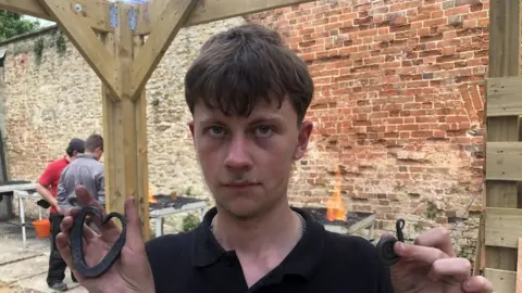 BBC Thomas holding up objects that he has made