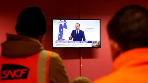 Reuters French SNCF railway workers on strike watch French Prime Minister Edouard Philippe deliver a speech on the government's pensions reform plans, at Strasbourg railway station, France